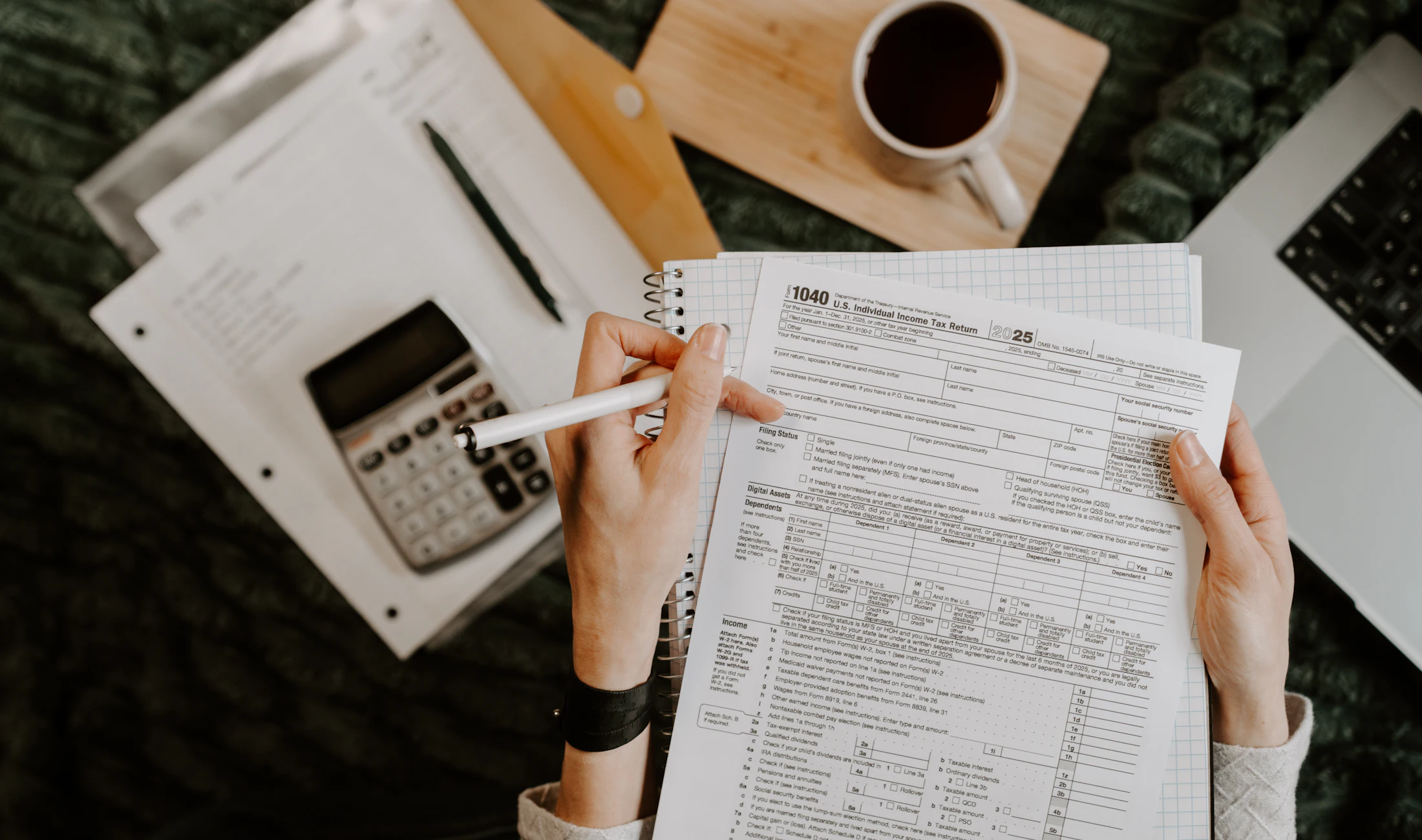 Hands reviewing financial documents next to a calculator and laptop